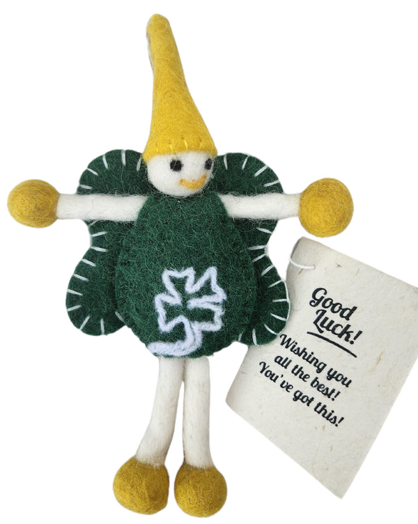 A handmade felt 'Good Luck' fairy/pixie with a yellow hat, green body, white legs, and yellow feet, accompanied by a paper tag that reads 'Good Luck!'.