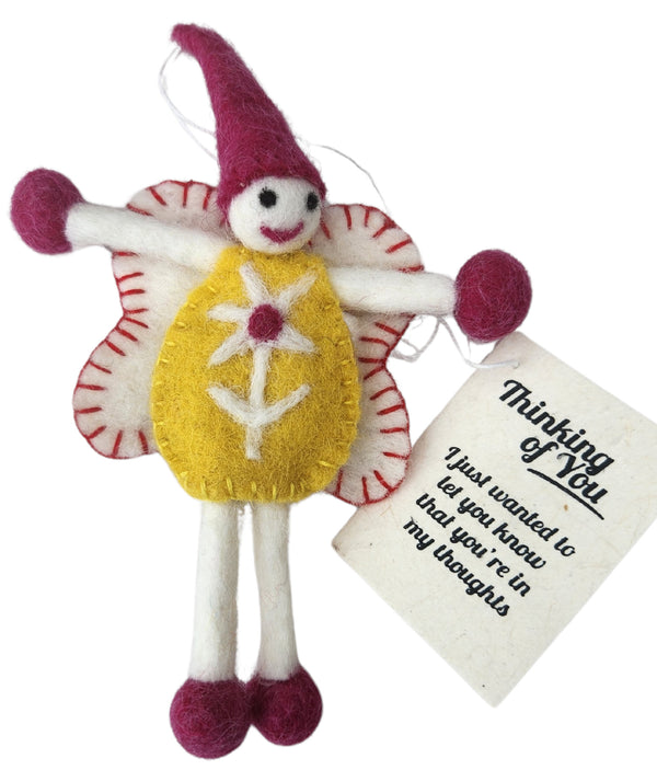 A handmade felt fairy keepsake/gift tag with a yellow dress, white wings with red stitching, and a magenta pointed hat. It has a white paper tag that reads 'Thinking of You. I just wanted to let you know that you're in my thoughts'.