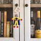A small handmade felt superhero doll with a 'You're My Hero!' tag hangs on a white wooden cabinet door, styled in a home setting.