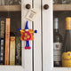 A felt fairy/pixie keepsake hanging from a cupboard door. The 'Well Done' gift tag is shown.