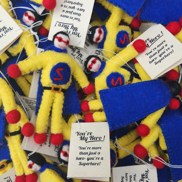 A pile of handmade yellow and blue felt superhero-themed gift tags, each attached to a white paper tag that reads 'You're My Hero!'.