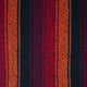 Close-up of a fabric swatch from mexican baja hoody with shades of red, orange  and black striped pattern