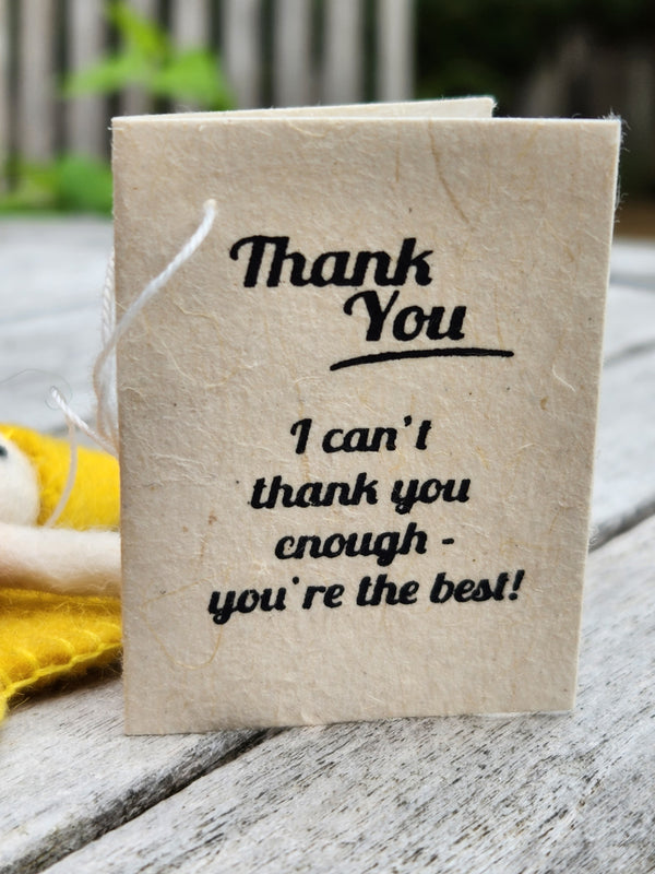 A handmade paper Thank you message with black printed text reading 'Thank You. I can't thank you enough - you're the best!' resting on a weathered wooden surface.